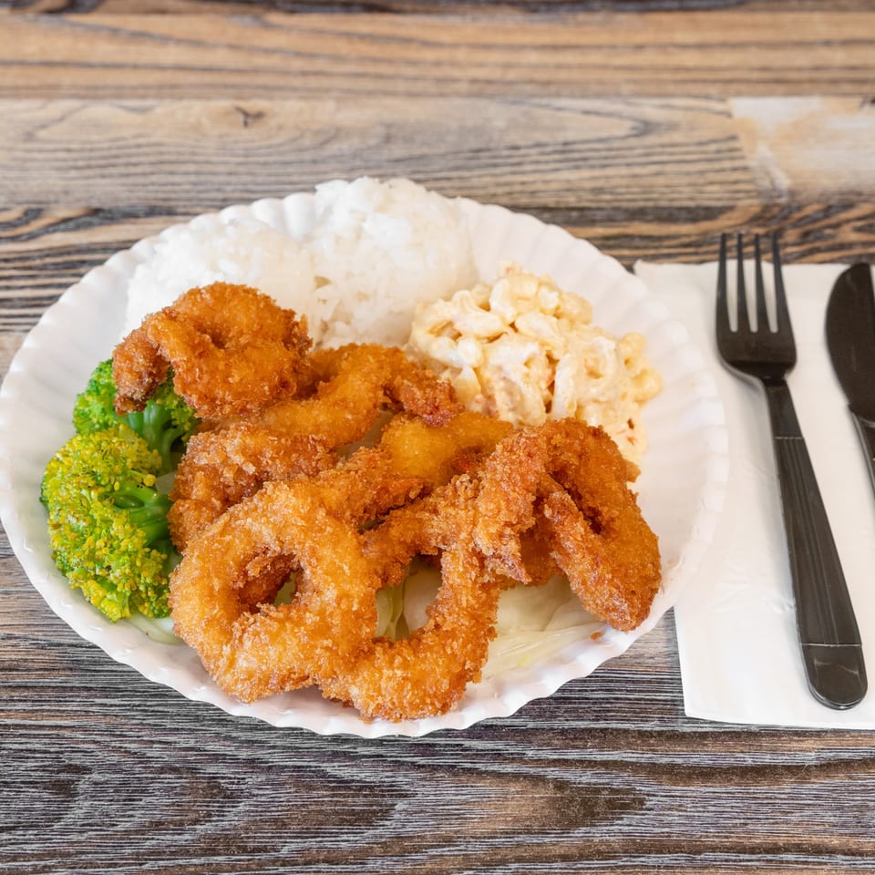 Plate of crispy breaded shrimp with white rice, broccoli, and creamy macaroni salad on a wooden table.