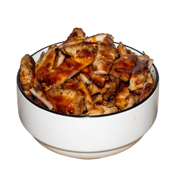 A white bowl filled with sliced grilled chicken pieces, generously coated in a rich, glossy brown sauce.