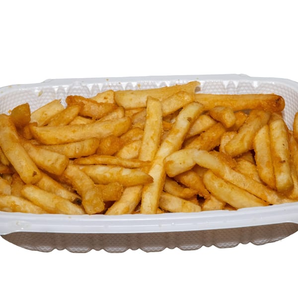 Golden-brown french fries, some seasoned, fill a white rectangular takeout container.