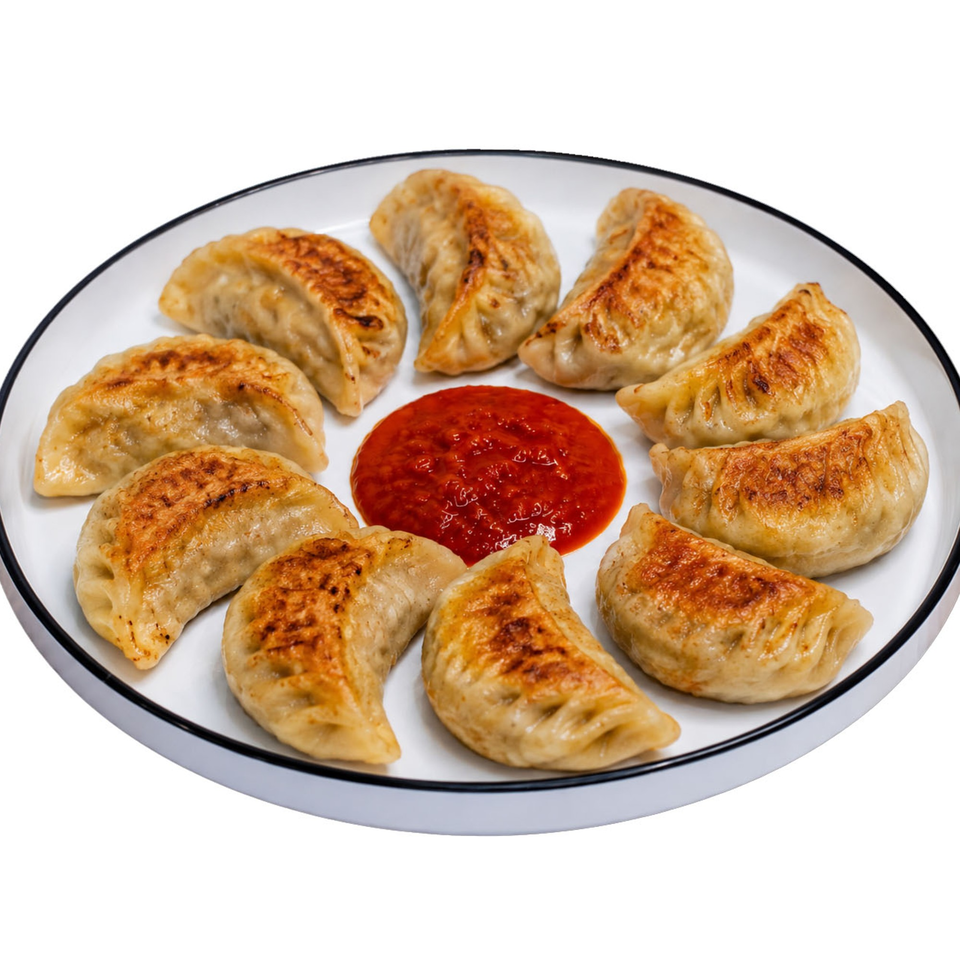 Golden pan-fried dumplings with crispy edges encircling a red chili dipping sauce on a white plate.