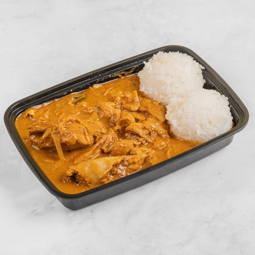 Hawaiian chicken curry with rice in a black takeout container on a white marble surface.