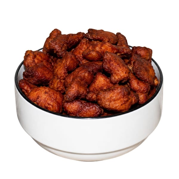 A white bowl filled with numerous pieces of crispy, dark brown fried chicken.